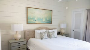 A neatly arranged bedroom with a bed, two bedside tables, a painting, and a door.