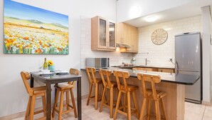 Une cuisine moderne avec des meubles en bois, un réfrigérateur en acier inoxydable et un coin repas avec des chaises en bois.