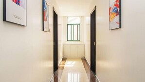 A hallway with a polished floor, a window with green frames, and framed artwork on the walls. - Lizhou Mountain Villa (Shengsi)