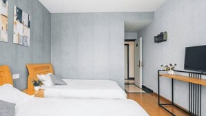 A modern hotel room with two single beds, a wooden nightstand, a TV on a black stand, and a small table with a vase. - Lizhou Mountain Villa (Shengsi)