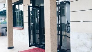 A hotel entrance with a red carpet, glass doors, and a view of the outdoor area. - Lizhou Mountain Villa (Shengsi)