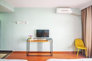 A hotel room with a bed, a desk with a TV, a yellow chair, and an air conditioning unit. - Lizhou Mountain Villa (Shengsi)