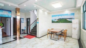 A hotel lobby with a marble floor, a staircase, a dining area with a table and chairs, and a painting on the wall. - Lizhou Mountain Villa (Shengsi)