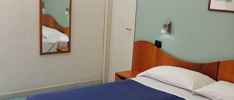 Une chambre à coucher avec un lit, une table de chevet, un miroir et une porte.