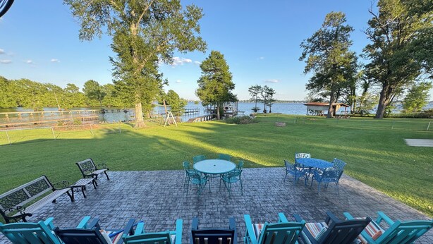 Un patio con mobiliario exterior, una mesa y vistas a un lago.