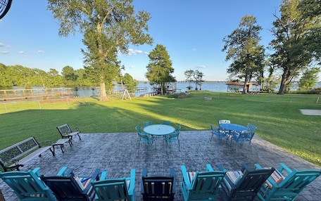 A patio with outdoor seating, a table, and a view of a lake.