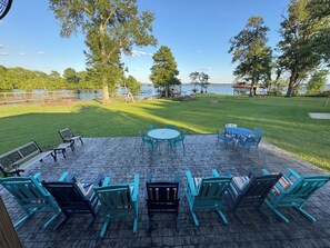 A patio with outdoor seating, a table, and a view of a lake. - Lakefront quiet Charming 3-bedroom house with WiFi and AC in serene Shreveport. (Shreveport)