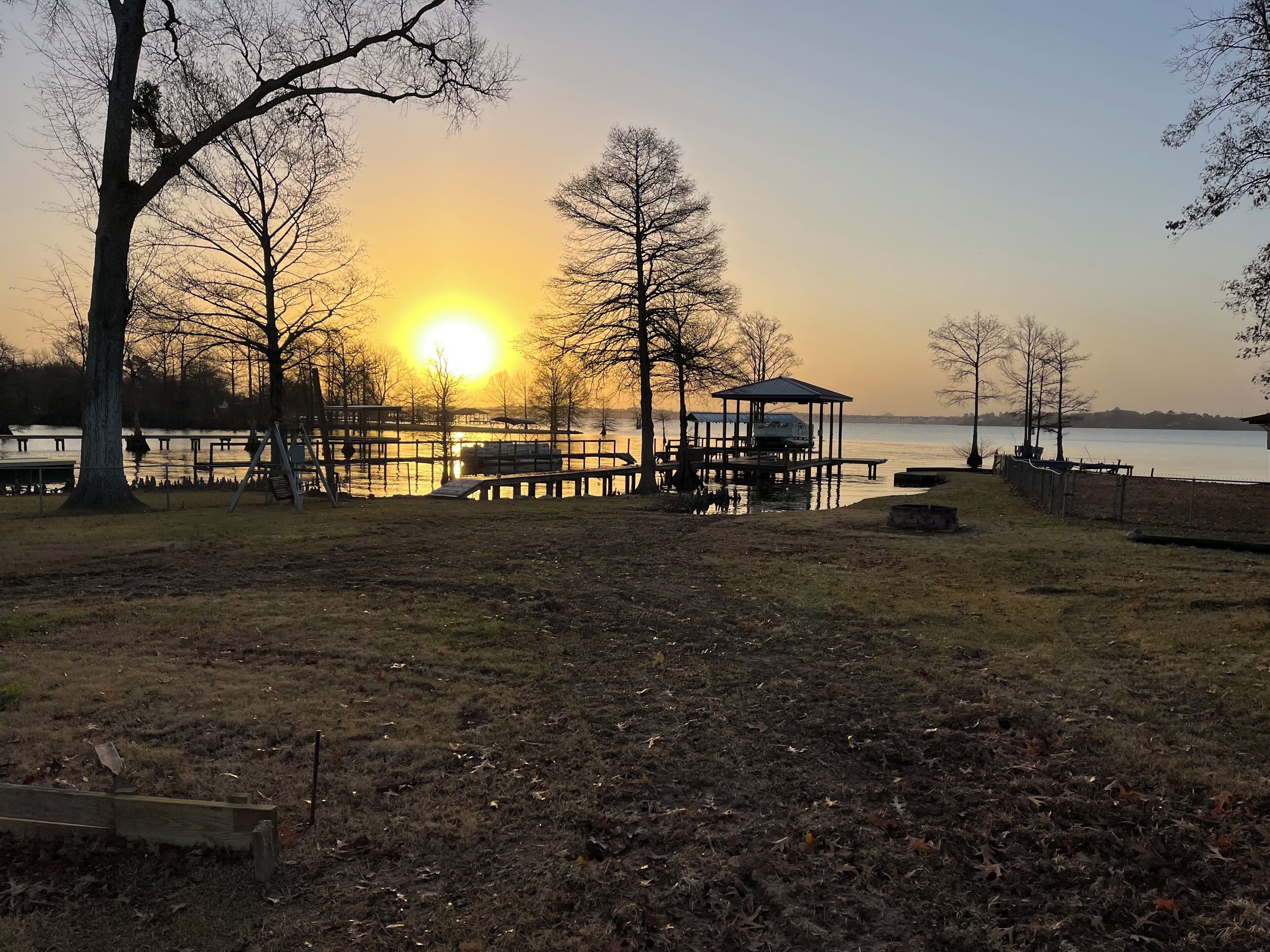 A lakeside park with a gazebo, wooden deck, and benches.
