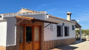 Un edificio de dos plantas con techo de tejas, puerta de madera y base de piedra.