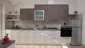 A modern kitchen with white cabinets, a stainless steel refrigerator, and a gas stove.