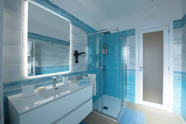 A modern bathroom with a large mirror, white vanity, and a glass shower enclosure.