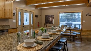 Una cocina con encimeras de granito, gabinetes de madera, un ventanal grande y una zona de comedor con bancos y mesas.