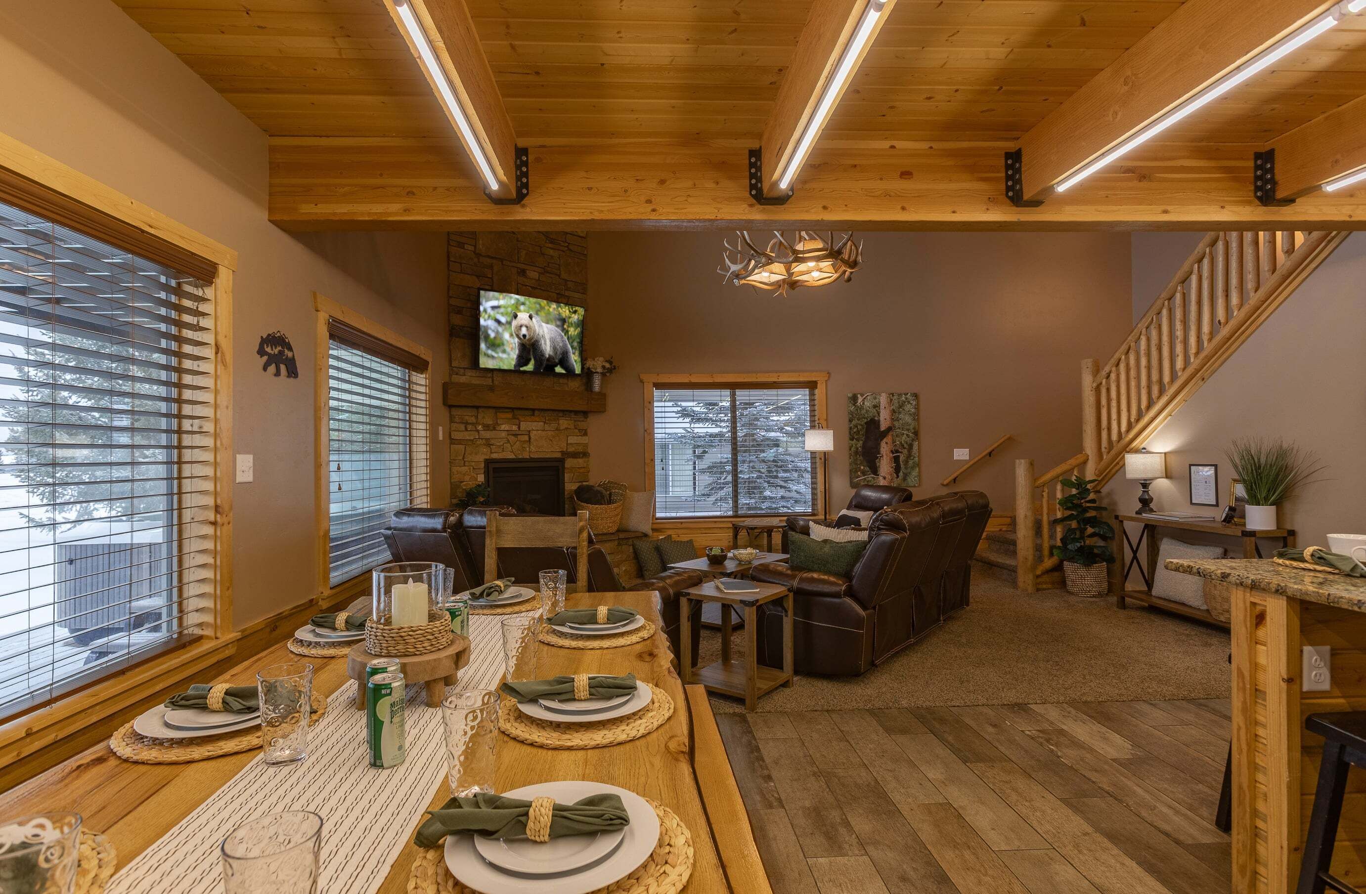 Un interior acogedor con comedor listo para cuatro, chimenea, televisor y escalera.