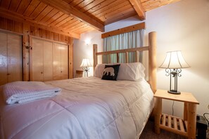 Camera da letto con struttura in legno, un letto grande, due comodini con lampade e un'armadio in legno.