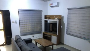Un espacio habitable compacto con sofá, una mesita y televisor montado en un estante de madera.