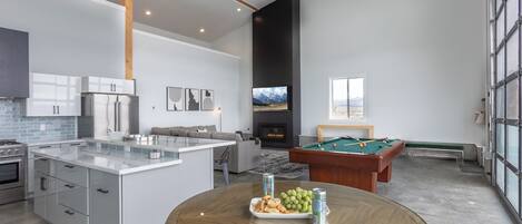 Una cocina moderna con una isla central, mesa de billar y chimenea.