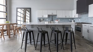 Uma cozinha moderna com uma ilha grande, banquetas e uma mesa de jantar com cadeiras.
