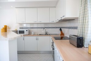 Une cuisine moderne avec des meubles blancs, un four à micro-ondes, un grille-pain et un évier.