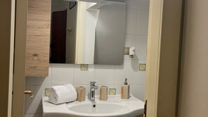 Ein Badezimmer mit weißem Waschbecken, Holzschrank und Spiegel.