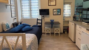 Ein gemütliches Schlafzimmer mit Bett, Schreibtisch und einer kleinen Küchenzeile.