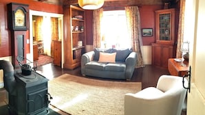 Een gezellige woonkamer met een retro fornuis, een blauwe bank en een witte fauteuil.