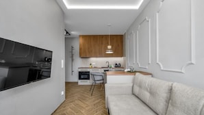 Una cocina moderna con armarios de madera, un área de comedor con sofá gris y suelo con patrón de espiga.