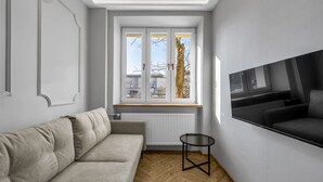 Una sala de estar moderna con un sofá, una mesita y un televisor montado en la pared.