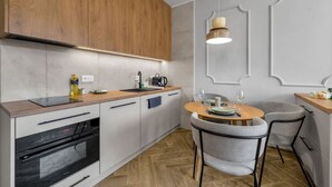 Una cocina moderna con armarios de madera, horno empotrado y comedor con una mesa redonda y sillas.