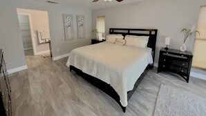 A bedroom with a bed, nightstands, a ceiling fan, and artwork on the walls.