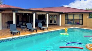 A swimming pool with lounge chairs and a covered patio area.