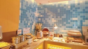A buffet area with various food items and a tiled wall.