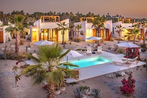 Un resort moderno con varias villas, piscina y zonas de estar al aire libre.