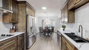 A modern kitchen with wooden cabinets, stainless steel appliances, and a central island with seating. - Spacious 5-bedroom house with WIFI and newly furnished in fabulous Arlington. (Arlington)