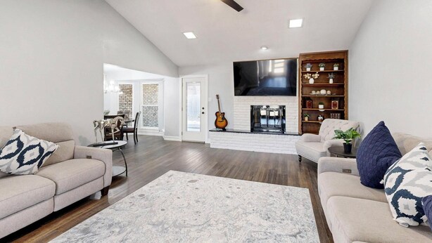 A spacious living room with a fireplace, a television mounted on the wall, and a bookshelf. - Spacious 5-bedroom house with WIFI and newly furnished in fabulous Arlington. (Arlington)