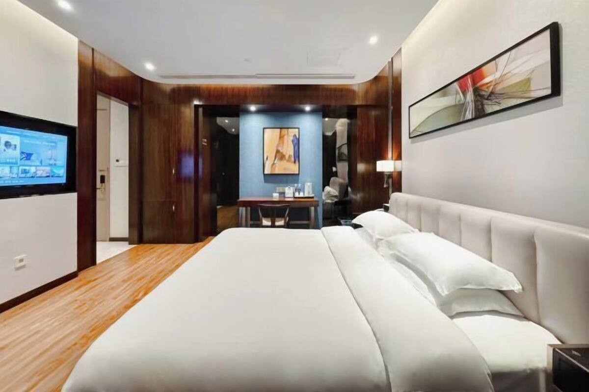 A modern hotel room with a large bed, a desk, and a TV.