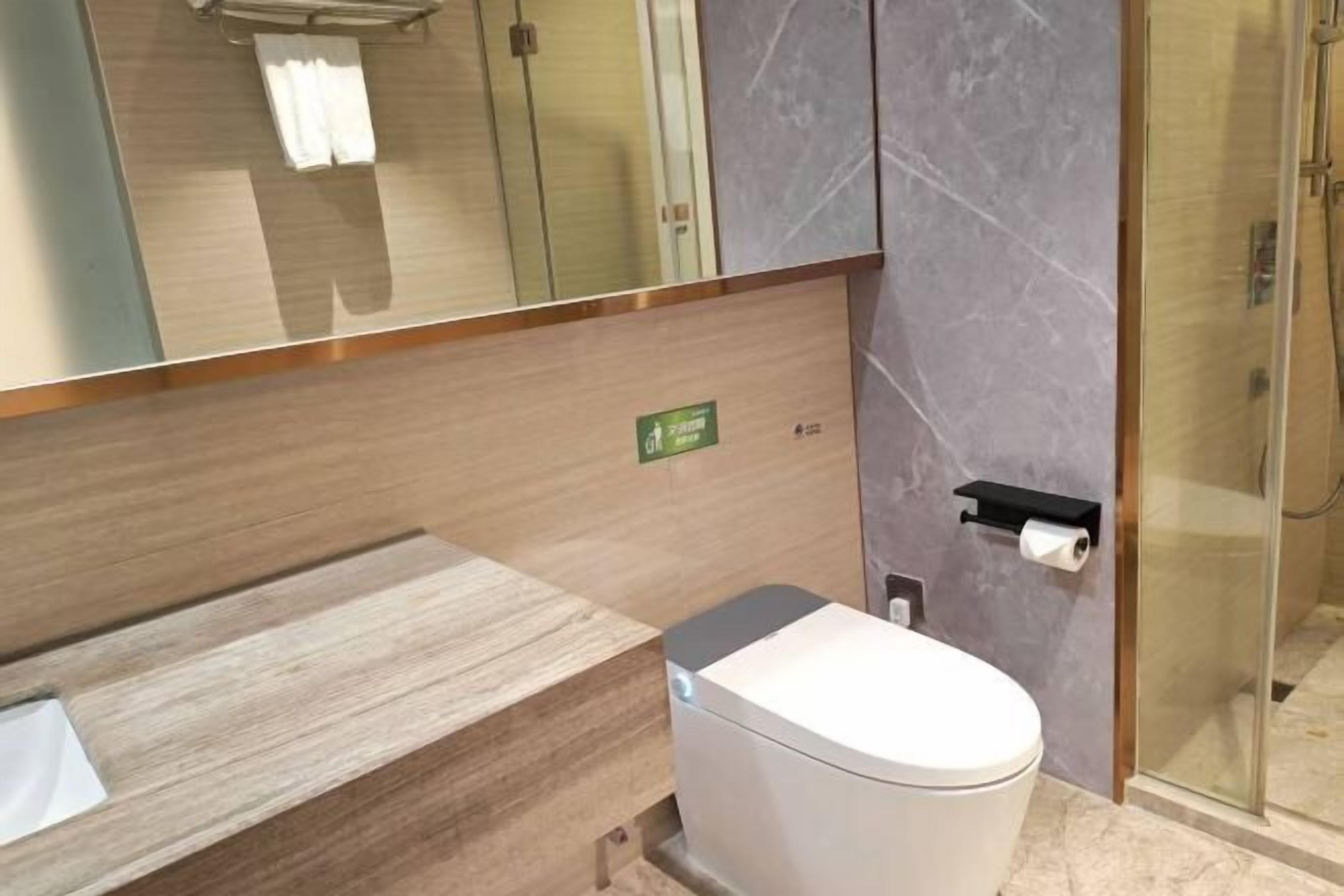 A modern bathroom with a toilet, a sink, a towel rack, and a glass shower enclosure.