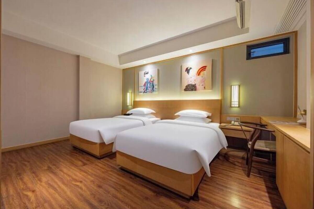 A hotel room with two beds, a desk, and a chair.
