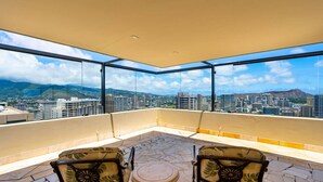 Un balcon avec deux chaises et une petite table, offrant une vue sur la ville.