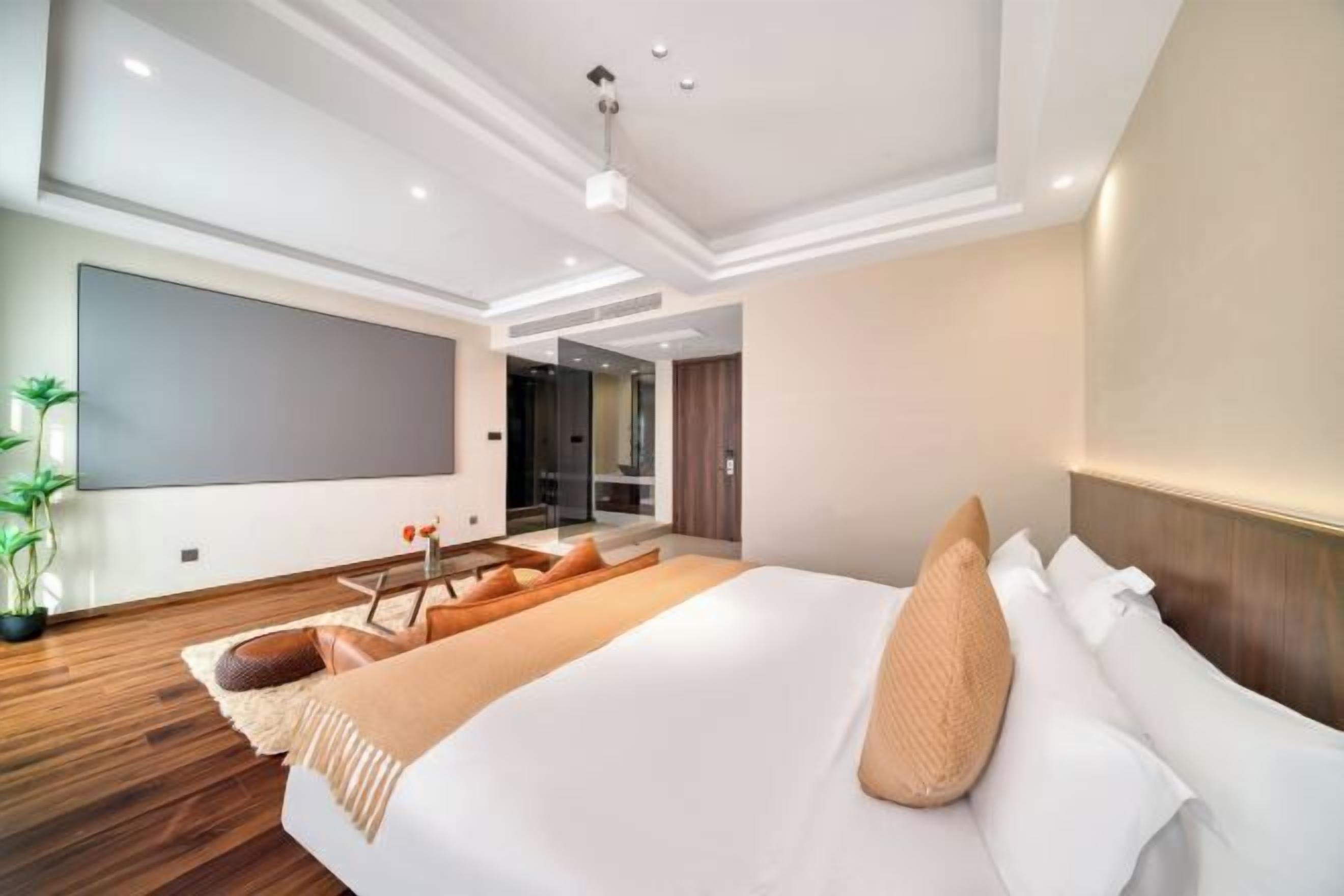 Une chambre d’hôtel moderne dotée d’un grand lit, d’un téléviseur à écran plat et d’un plancher en bois.