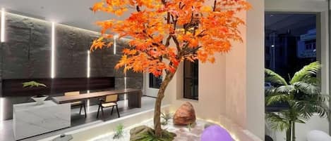 Un interior moderno con un árbol central, zona de estar y un diseño minimalista.