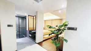 A modern hotel room with a bed, a plant, and a sliding door leading to a balcony. - Xingji Hotel (Tiantai County)
