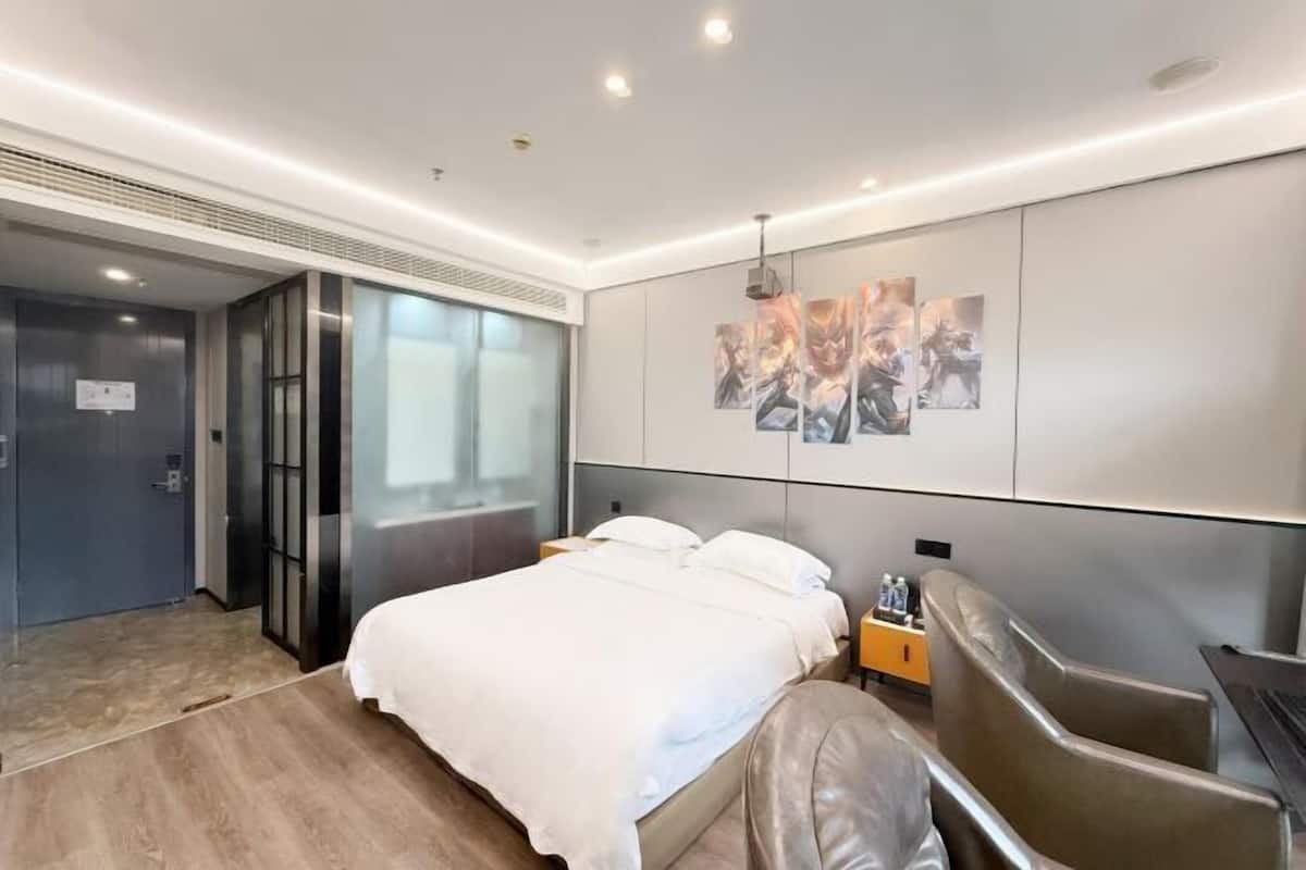 A modern hotel room with a bed, a seating area, and a wall with artwork.