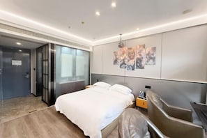 Une chambre d’hôtel moderne comprenant un lit, un coin salon et un mur décoré d’œuvres d’art.