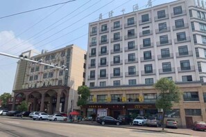 A multi-story building with a commercial ground floor, featuring several storefronts and parked cars. - Xingji Hotel (Tiantai County)