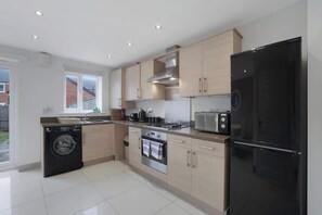 A modern kitchen with a washing machine, oven, microwave, and refrigerator. - Spacious Retreat for 10 Perfect for Families (Bowburn)
