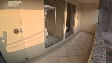 A room with a sliding glass door leading to a balcony, tiled floor, and a door with a handle.