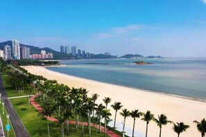 A coastal cityscape with a beach, palm trees, and high-rise buildings. - Huating Hotel (Zhuhai Youtehui Branch) (Zhuhai)