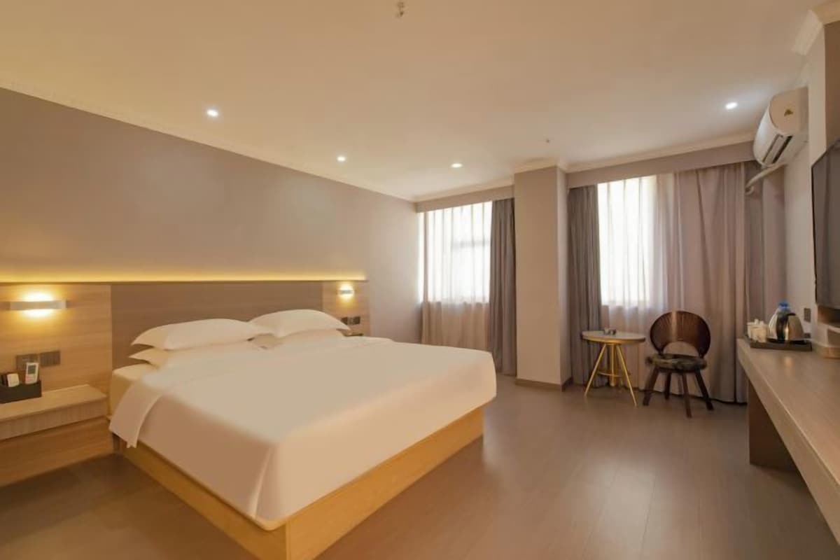Una habitación de hotel con una cama grande, mesitas de noche, una pequeña mesa redonda y una silla.
