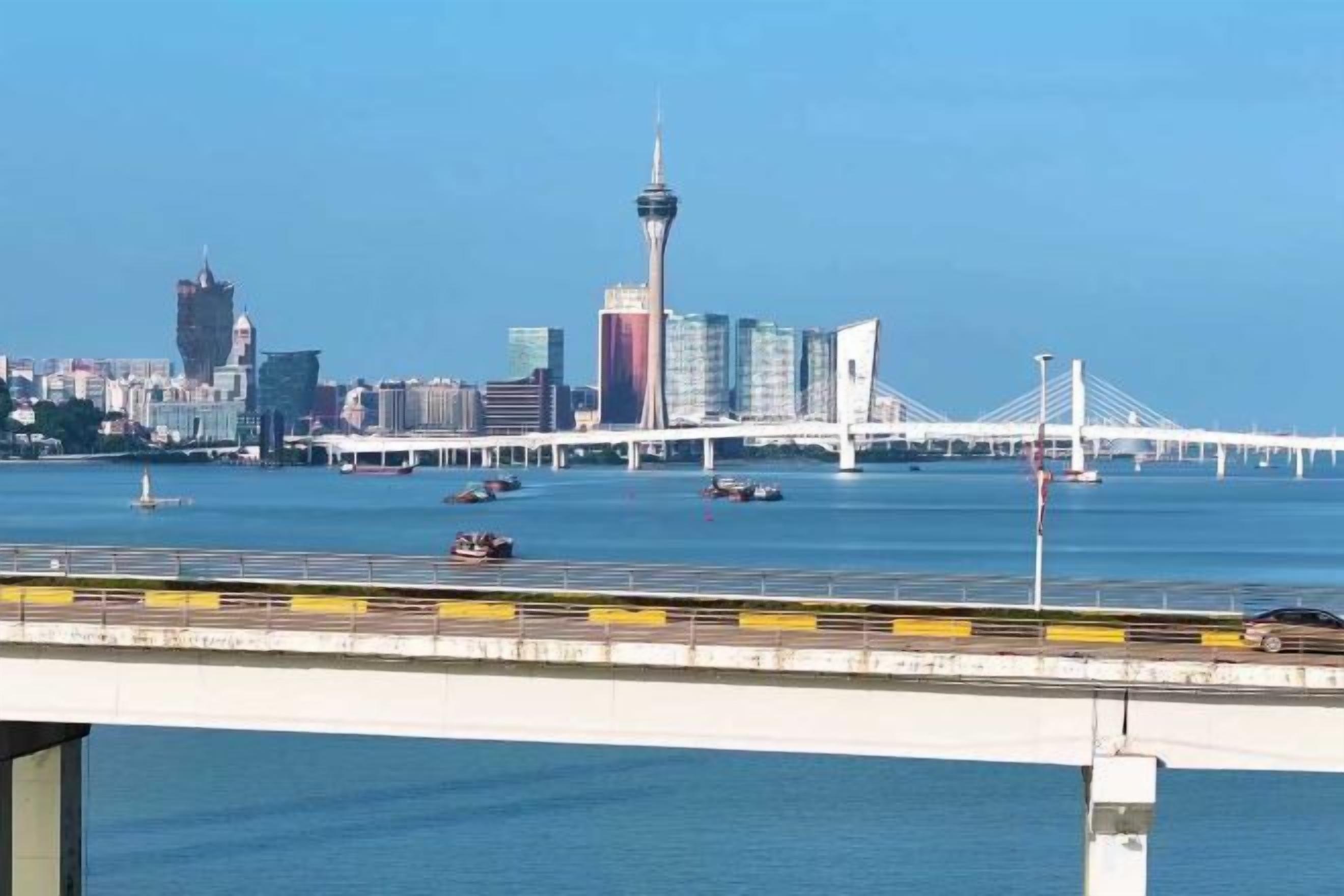 A city skyline with a prominent tower and a bridge over water.