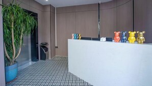 A reception area with a white counter, a potted plant, and a row of colorful bear figurines. - Huating Hotel (Zhuhai Youtehui Branch) (Zhuhai)